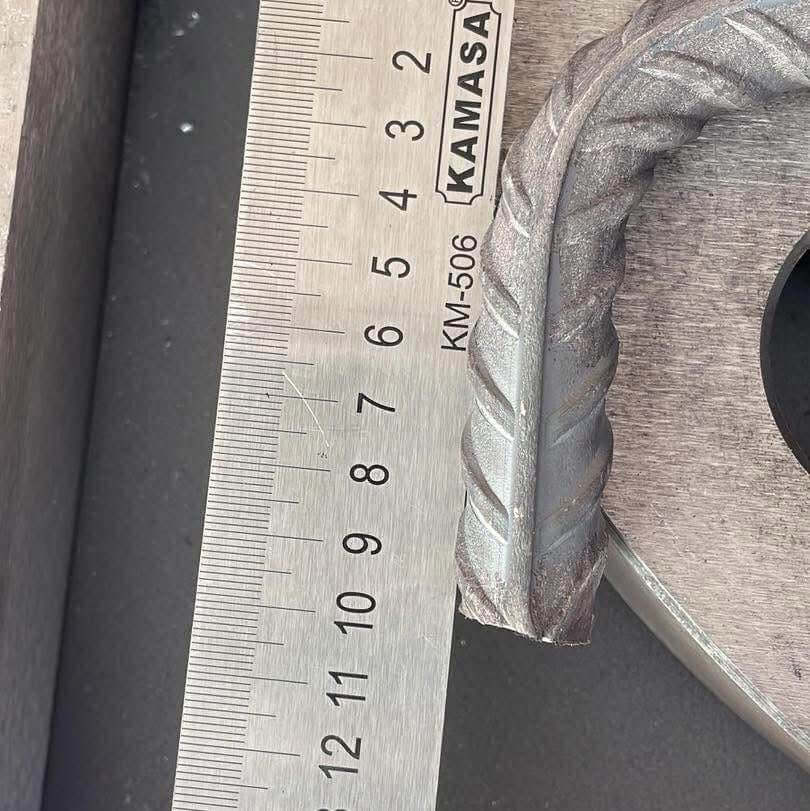Medición de fierro corrugado con regla, destacando su diseño y dimensiones para doblado en maquinaria CNC.