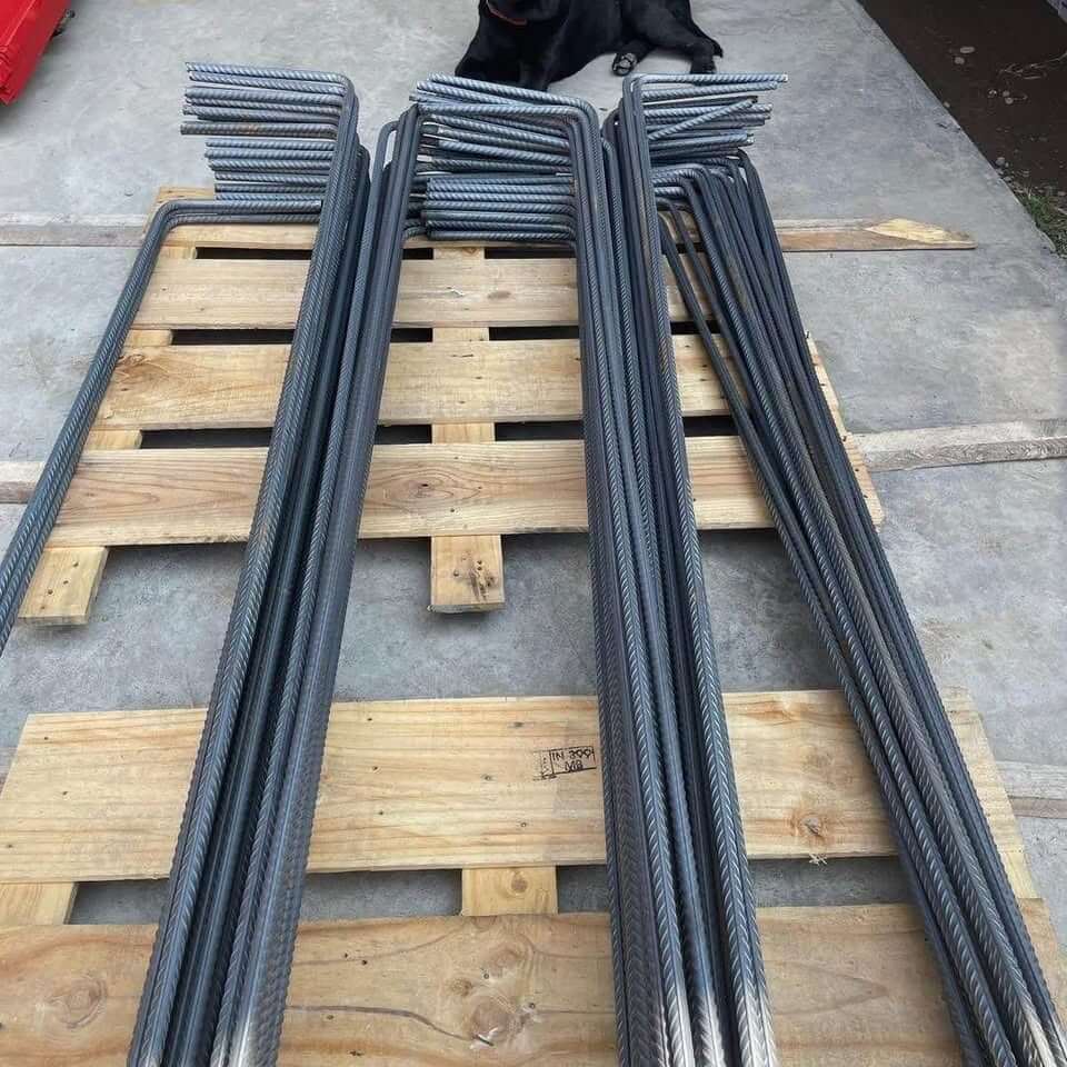 Variedad de varillas de fierro corrugado apiladas sobre un pallet de madera.